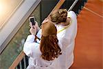 High angle view of two female doctors on hospital balcony using smartphone touchscreen