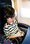 Boy on airplane selecting music on mp3 player
