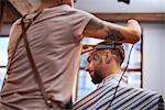 Hairdresser shaving customer's hair