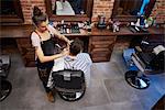 Hairdresser shaving customer's hair with straight razor