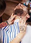 Hairdresser shaving customer's beard