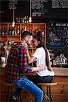 Couple on stools in coffee shop face to face smiling