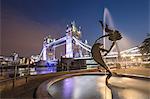 The Girl With A Dolphin Fountain frames Tower Bridge reflected in the River Thames at night, London, England, United Kingdom, Europe