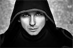 Mysterious Man in Black Hoodie. Sexy Hero Guy. Pastor or Wizard in Robe. Assassin or Witcher with Strong Face Expression in Cloak. Dark Magician Black and White Photo. Fantasy Book Cover Concept.