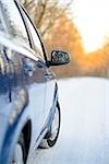 Close up Image of Side Rear-view Mirror on a Blue Car in the Winter Landscape with Evening Sun