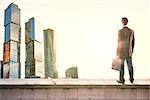 Businessman standing with back against morning city, panoramic view