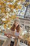 Autumn getaways in Paris. young tourist woman on embankment near Eiffel tower in Paris, France looking at the map