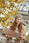 Autumn getaways in Paris. young tourist woman on embankment in Paris, France with map