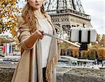 Autumn getaways in Paris. young elegant woman on embankment near Eiffel tower in Paris, France taking selfie using selfie stick
