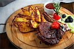 Grilled beef steak with baked potatoes and vegetables on plate