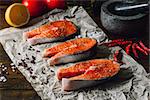 Three Salmon Steaks Prepared for Cooking with Chili Peppers and Other Spices.