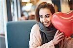 Happy smiling woman with balloon in the form of heart in a cafe. Couple in love on a date. Love story and Valentines Day concept