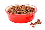 Dry cat food in a red bowl, some biscuits spilled beside, isolated on a white background