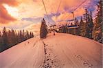 Winter mountains panorama with ski slopes and ski lifts in a cloudy day. Sunset soft light with dramatic orange sky. Vintage toning effect. Bukovel, Carpathians, Ukraine, Europe