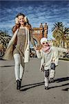 in Barcelona for a perfect winter. Full length portrait of happy trendy mother and daughter near Arc de Triomf in Barcelona, Spain walking