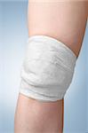 Injured female knee with white gauze bandage