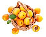 Fresh apricot with green leaf in wicker basket still life of fruits, isolated on white background and copyspace top view