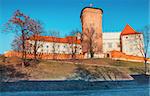 Wawel castle with brick tower, landmark in Krakow old town, Poland. Winter morning landscape with bright sunlight and trees with long shadows