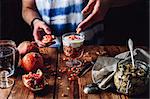 Man Decorates Dessert with Pomegranate Seeds. Series on Prepare Healthy Dessert with Pomegranate, Granola, Cream and Jam
