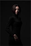 portrait of young elegant woman wearing black dress on black background. Fashion studio shot.