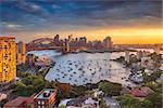 Cityscape image of Sydney, Australia with Harbour Bridge and Sydney skyline during sunset.