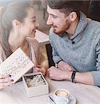 Two people, man and woman in cafe communicate, laughing and enjoying the time spending with each other. Couple in love on a date. A woman receives a gift from a man. Love story and Valentines Day concept