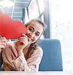 woman smiling and holding a large paper heart. Couple in love on a date. Love story and Valentines Day concept