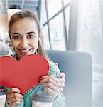 woman smiling and holding a large paper heart. Couple in love on a date. Love story and Valentines Day concept