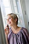 Woman talking on cell phone by window