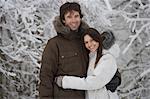 Couple by snow covered trees.