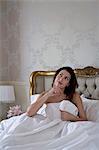 Young woman in bed looking puzzled