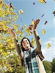 Woman with Autumn leaves in the air