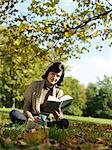 Woman under tree reading book in Autumn