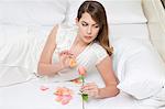 woman on bed counting petals of rose