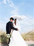 bride and groom walking under parasol