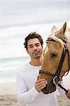 Man with brown horse on the beach