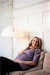 Pregnant woman on sofa phoning