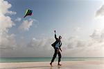 Businessman flying a kite on beach