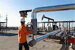 Worker adjusting pipes at oil field