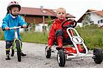 Toddler boys riding bike and go-cart