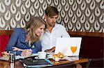 Couple studying with laptop in cafe