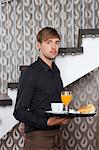 Waiter holding breakfast tray in cafe