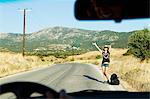 Woman hitch hiking on rural road