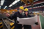 Workers reading blueprints in shipyard