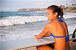 Surfer sitting with surfboard on beach