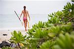 Surfer carrying surfboard on beach