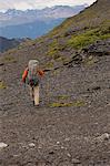 Hiker walking with sticks in rocky hills