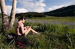 Hiker writing in grassy meadow