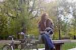 Woman sitting with bicycle in park