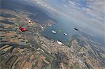 People skydiving over rural landscape